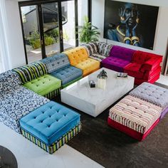 a living room filled with lots of colorful couches and ottomans on top of each other