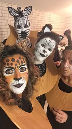some people are wearing animal costumes and posing for a photo with zebras on their faces