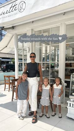 a woman standing next to two children in front of a store