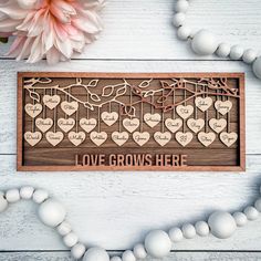 a wooden frame with hearts on it and the words love grows here