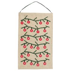 an embroidered wall hanging with cherries on the branch and numbers written in red ink