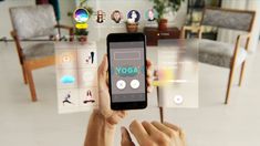 a person holding up a smart phone in front of a room with yoga icons on it