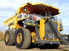 a large yellow dump truck parked on top of a dirt field