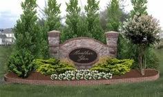 a large sign in the middle of a lush green field with trees and bushes around it