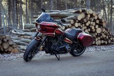 a red and black motorcycle parked in front of some logs