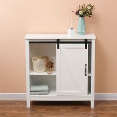 a white cabinet with sliding doors on the top and bottom, in front of a pink wall