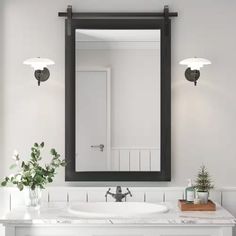 a bathroom with a sink, mirror and lights on the wall next to flowers in vases