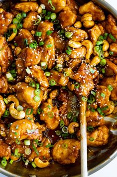 chicken and cashews with sesame seeds in a wok on a white surface