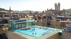 people are playing in an outdoor swimming pool on top of a building with spires