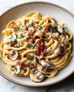 a plate of pasta with mushrooms, bacon and cheese on the top is sitting on a marble table