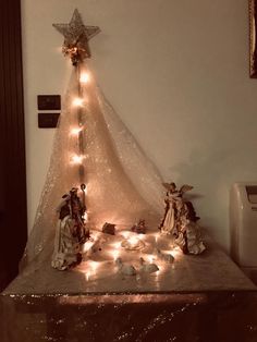 a christmas tree with lights on it and nativity figurines in the foreground