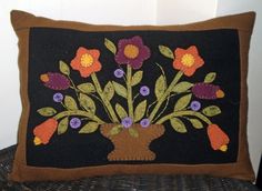 an embroidered pillow with flowers in a vase