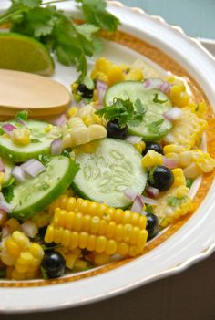 a salad with cucumbers, black olives, corn and cilantro