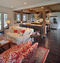 a living room filled with furniture and a kitchen in the backgroung area