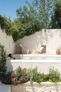 an outdoor jacuzzi in the middle of a garden with flowers and plants around it