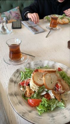 a person sitting at a table with a plate of food in front of them and a cell phone on the table