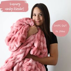 a woman holding a pink fluffy blanket over her shoulder with the words luxury monkey blanket behind it