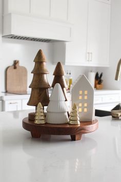 a white kitchen counter top with christmas trees on it and a small house in the middle