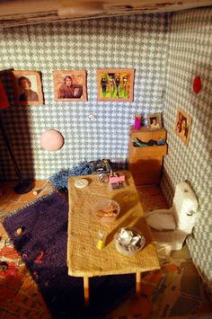 a doll house with a table and pictures on the wall, toilet and other furniture