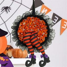 an orange and black wreath hanging from a shelf with halloween decorations on the wall behind it