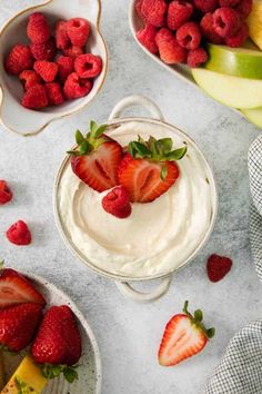 some strawberries are on top of a bowl of yogurt and other fruit