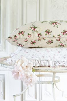 three pillows stacked on top of each other next to a white table with pink flowers