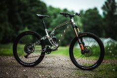 a bike parked on the side of a dirt road in front of green grass and trees