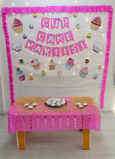 a pink table topped with cupcakes under a sign that says cup cake party