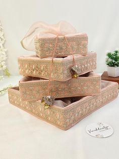 three pink boxes are stacked on top of each other, with ribbons tied around them