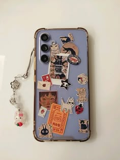 a cell phone case with various stickers on it and a keychain hanging from the back