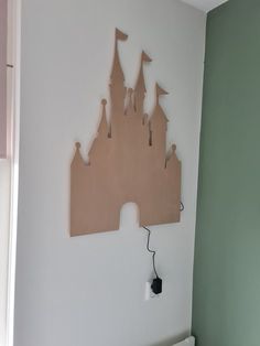 a wooden cutout of a castle is mounted on the wall above a crib