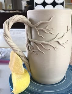 a ceramic mug sitting on top of a blue plate next to a piece of yellow sponge