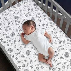 a baby laying on top of a white crib