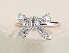 a diamond bow ring sitting on top of a white blanket