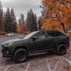 a black toyota rav parked in a parking lot next to trees with orange leaves