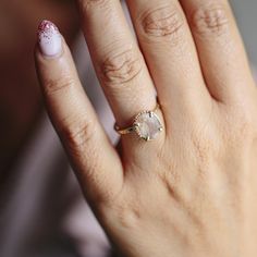 a close up of a person's hand with a ring on their finger and nail polish