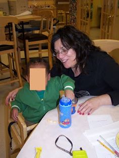 a woman sitting at a table with a child