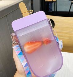 a person holding up a plastic case with two fish in it's water inside