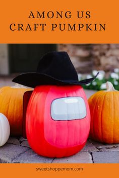 an orange pumpkin with a black hat on top and three white pumpkins behind it