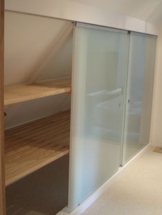 an attic bedroom with white walls and wood flooring on the side, along with glass sliding doors to let in natural light