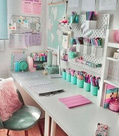 a white desk topped with lots of pink and blue items next to a wall mounted map