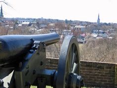 an old cannon sitting on top of a brick wall in front of a cityscape