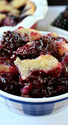 a bowl filled with blueberry cobble next to other pies