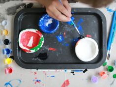 a child is painting with paints on a tray