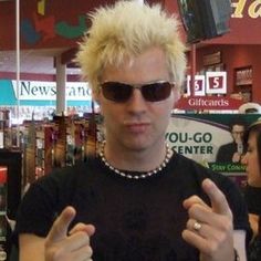 a man with blonde hair and sunglasses holding up two fingers