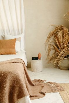 a bed with a brown blanket next to a potted plant