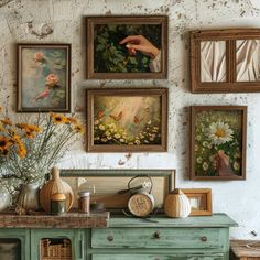 there are many paintings on the wall above a dresser and table with flowers in vases