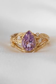 a close up of a ring with a purple stone in it on a white surface