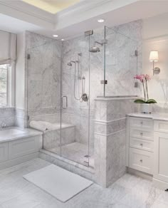 a white bathroom with marble flooring and walls, along with a walk in shower