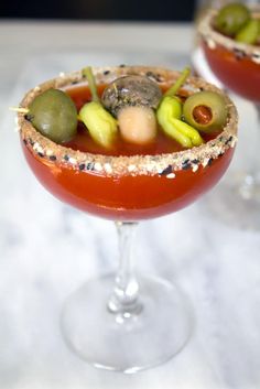 two glasses filled with different types of food on top of a white tableclothed surface